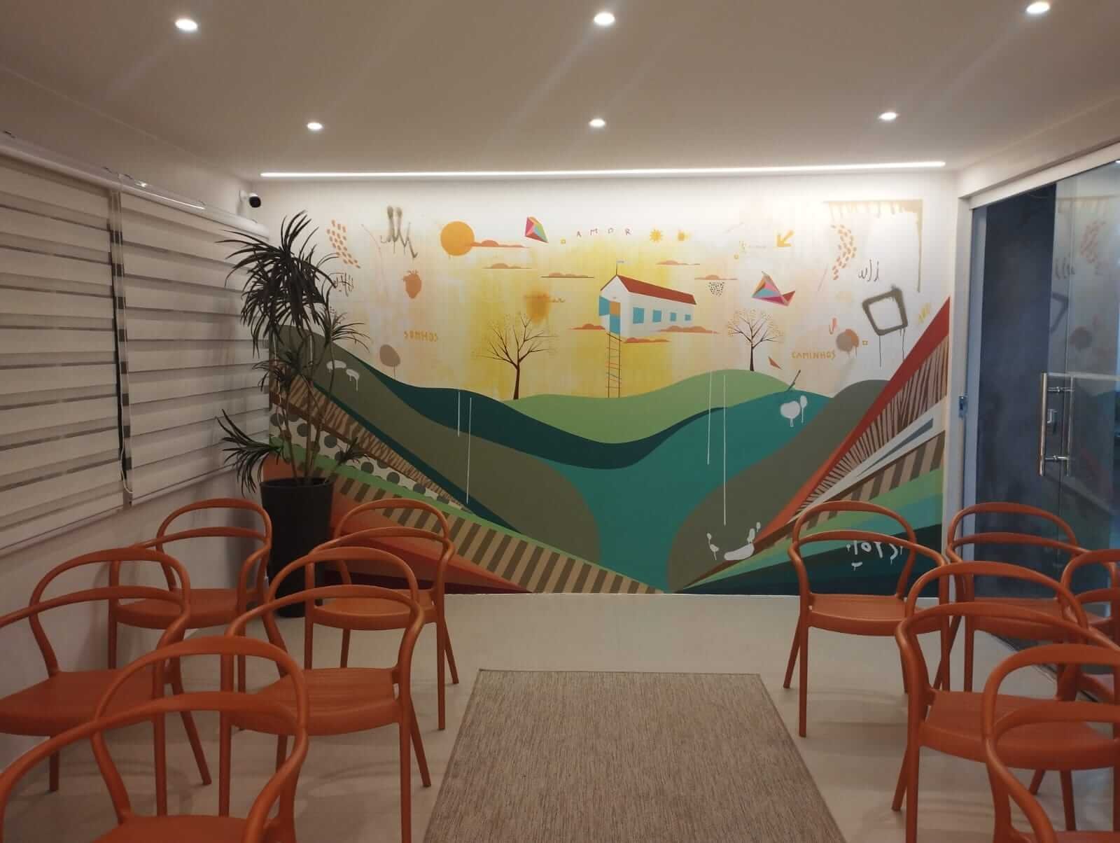 Vista da sala de cerimônias do Cartório de Sobradinho, com cadeiras laranja e painel artístico ao fundo